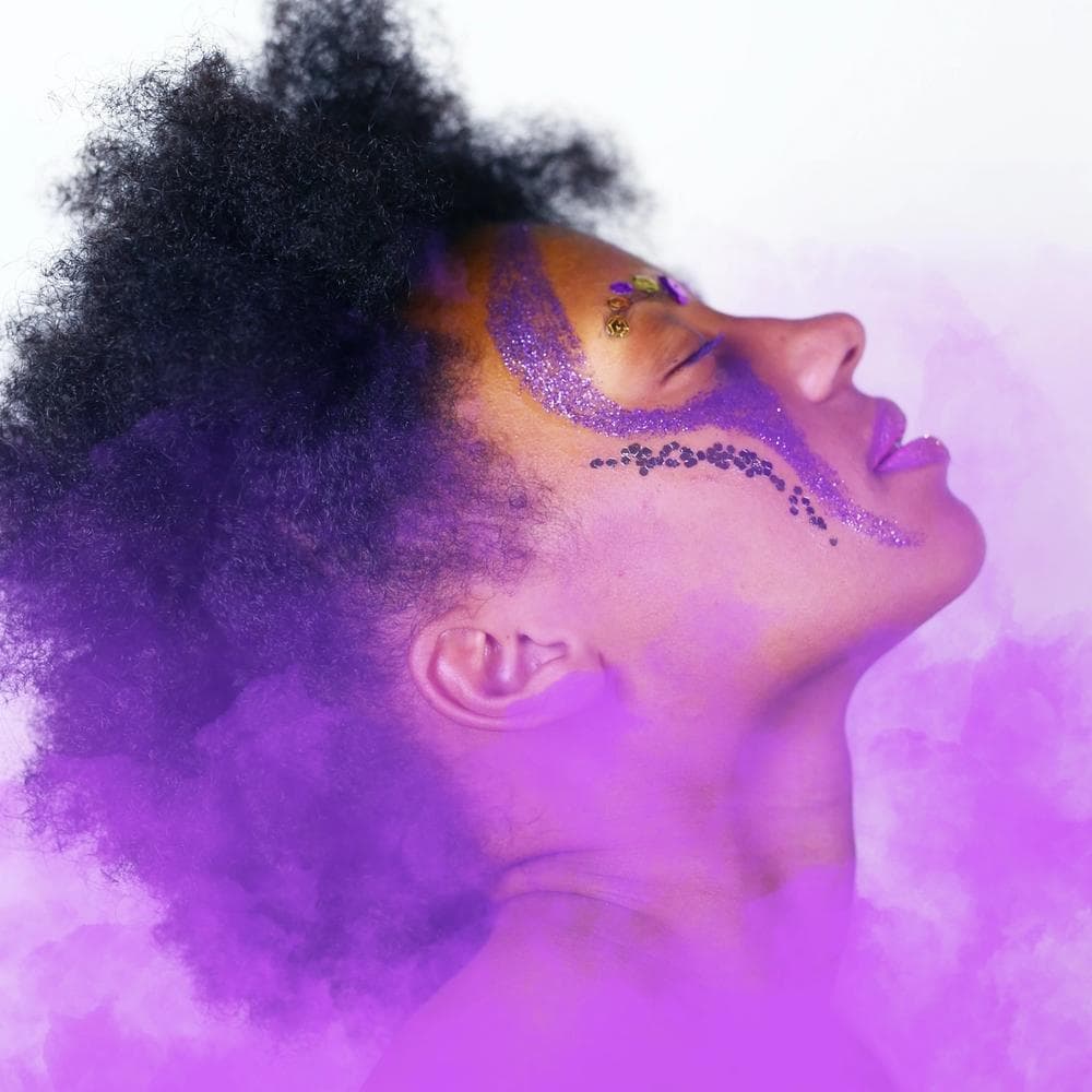 Black hair, female, with purple face paint and purple smoke effect on a white background, model